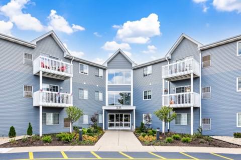 A large blue building with a white balcony and a red sign that says "Apartments".