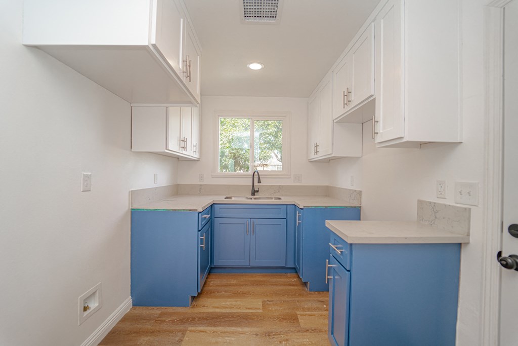 a kitchen with blue cabinets and white counters and a window