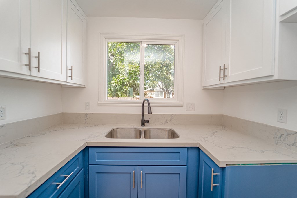 a kitchen with blue and white cabinets and a window