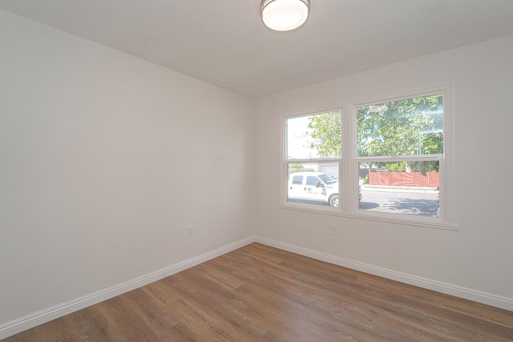 an empty living room with a window and wood flooring