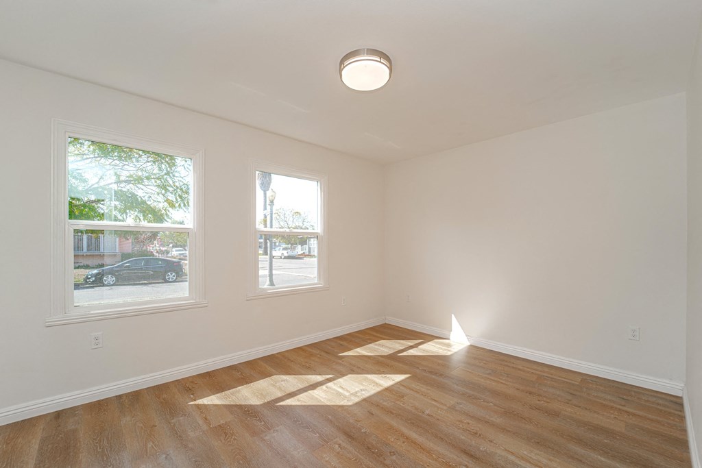 a living room with a hard wood floor and two windows