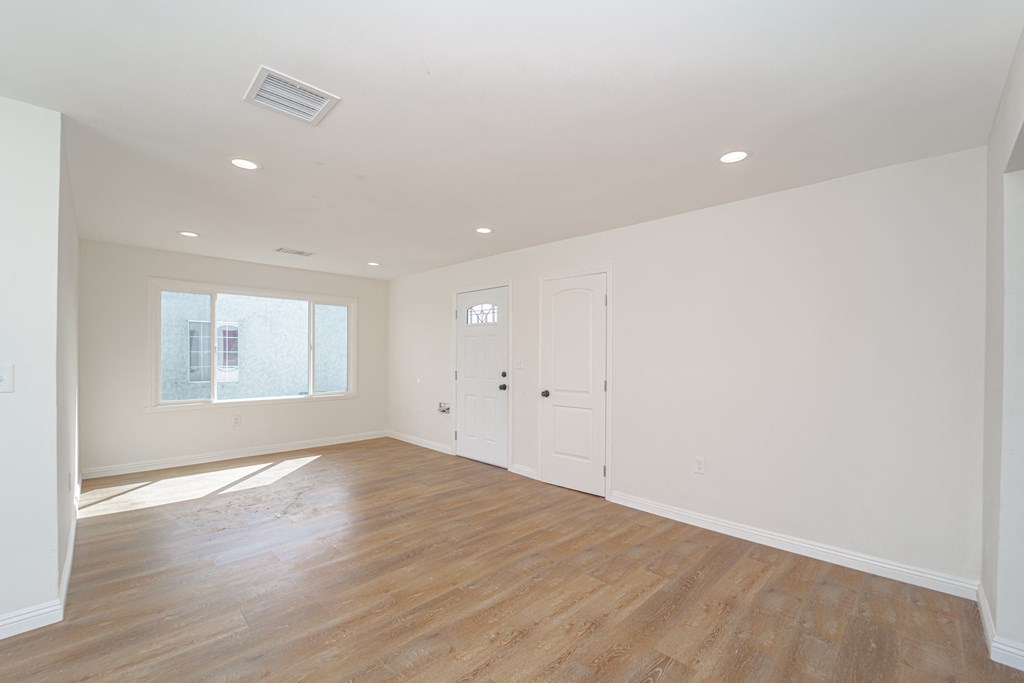 an empty living room with white walls and wood floors