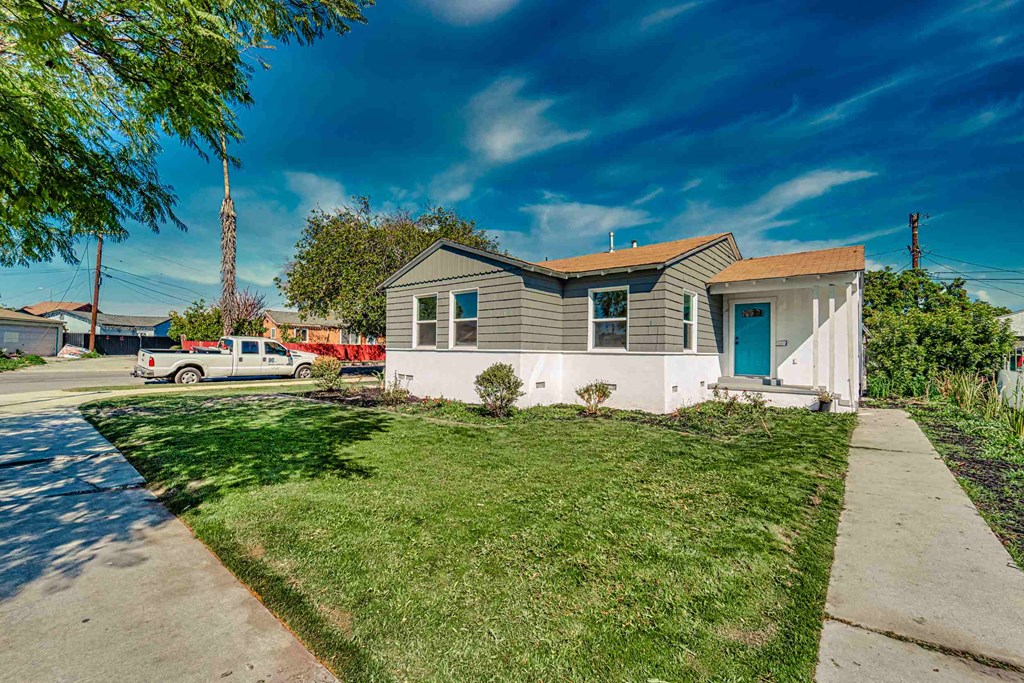 a small white and gray house with a sidewalk and grass
