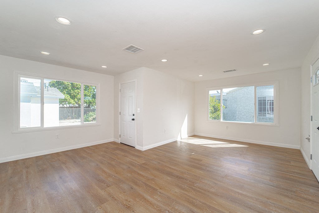 an empty living room with wood floors and white walls