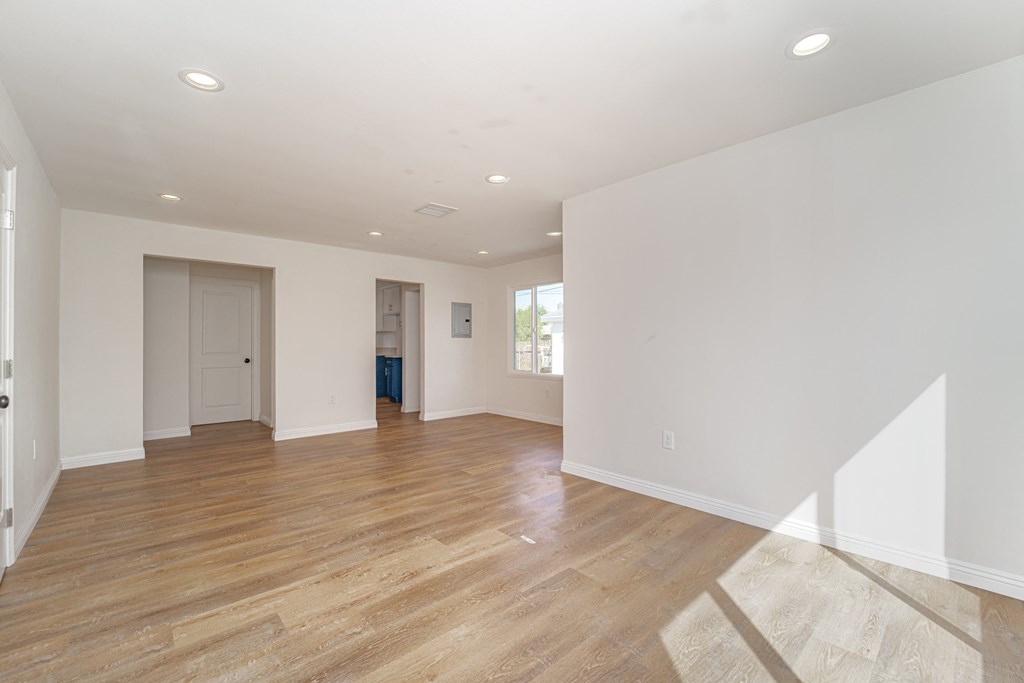 an empty living room with white walls and wood floors