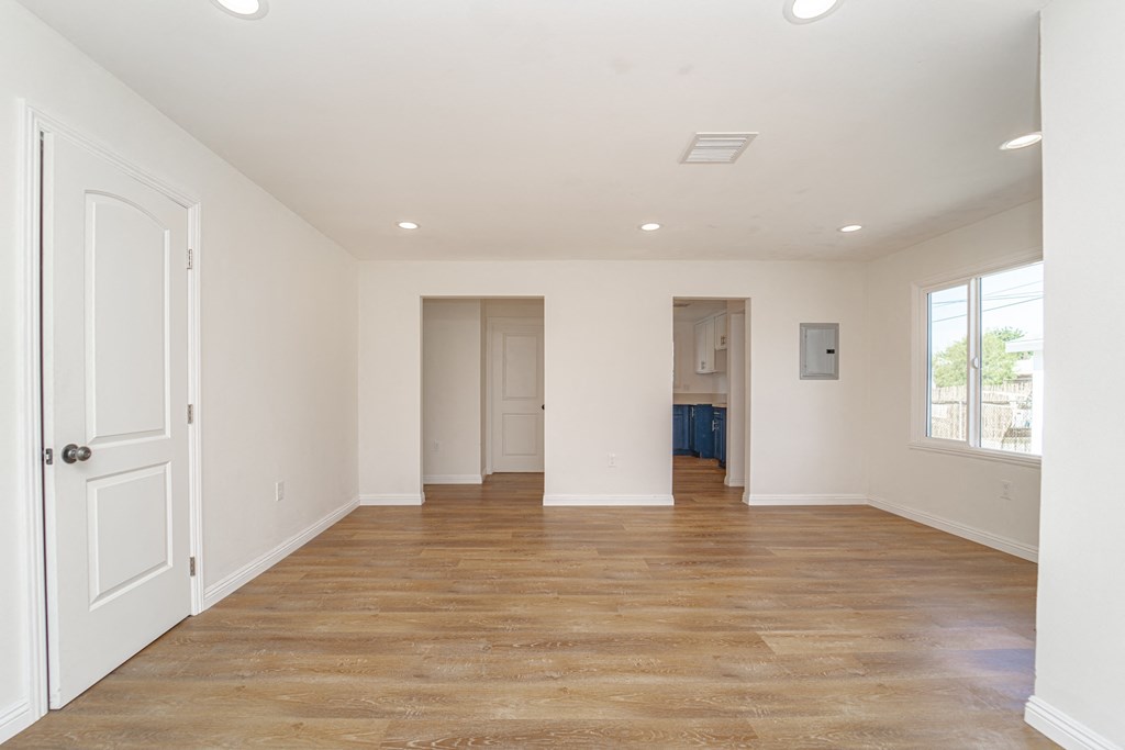 an empty living room with white walls and a wooden floor