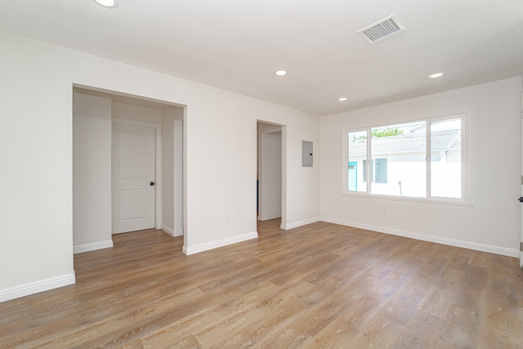 an empty living room with wood floors and white walls
