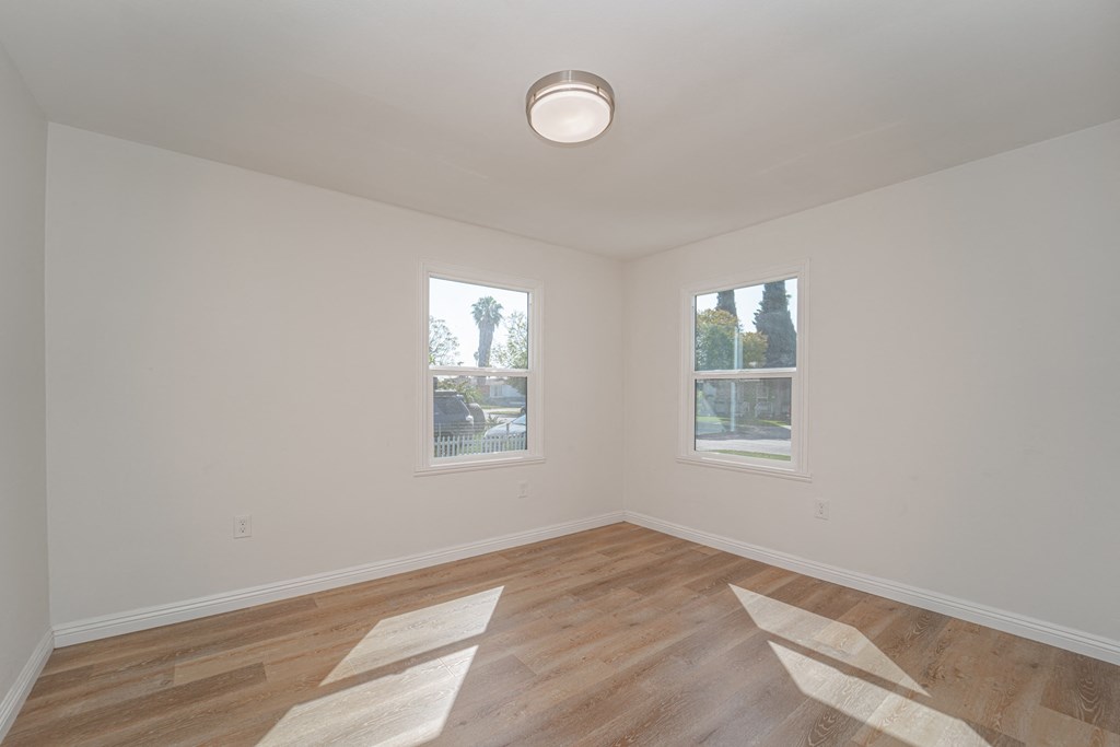 an empty living room with wood floors and two windows