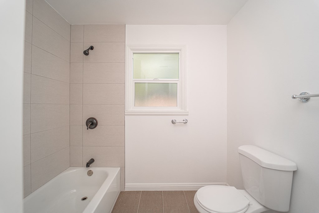 a bathroom with a toilet and a tub and a window