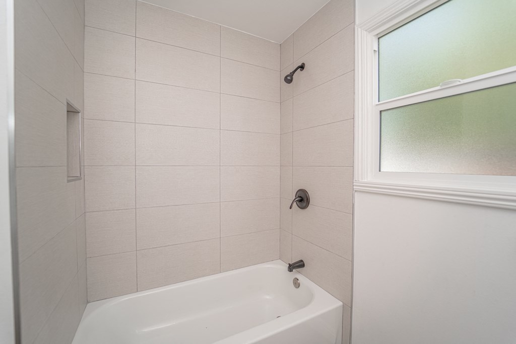 a white bathroom with a tub and a window