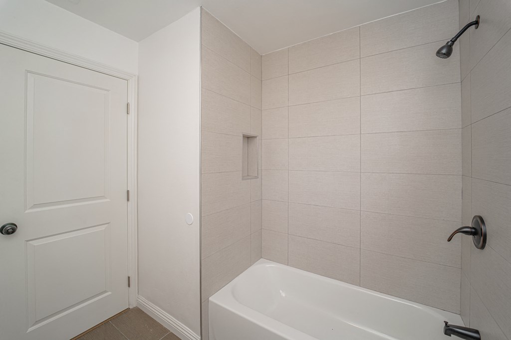 a white bathroom with a tub and shower and a white door