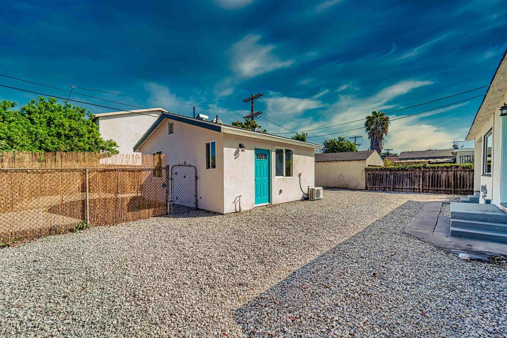 a white house with a blue door and a gravel driveway
