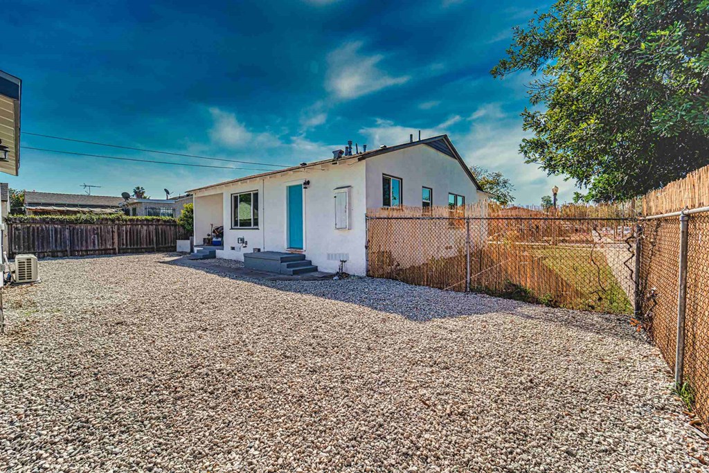 a white house with a fence and a gravel driveway