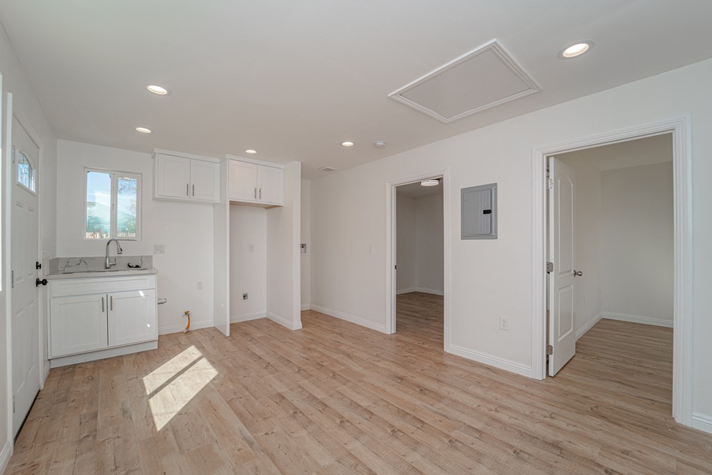 a kitchen and living room with white cabinets and a wooden floor
