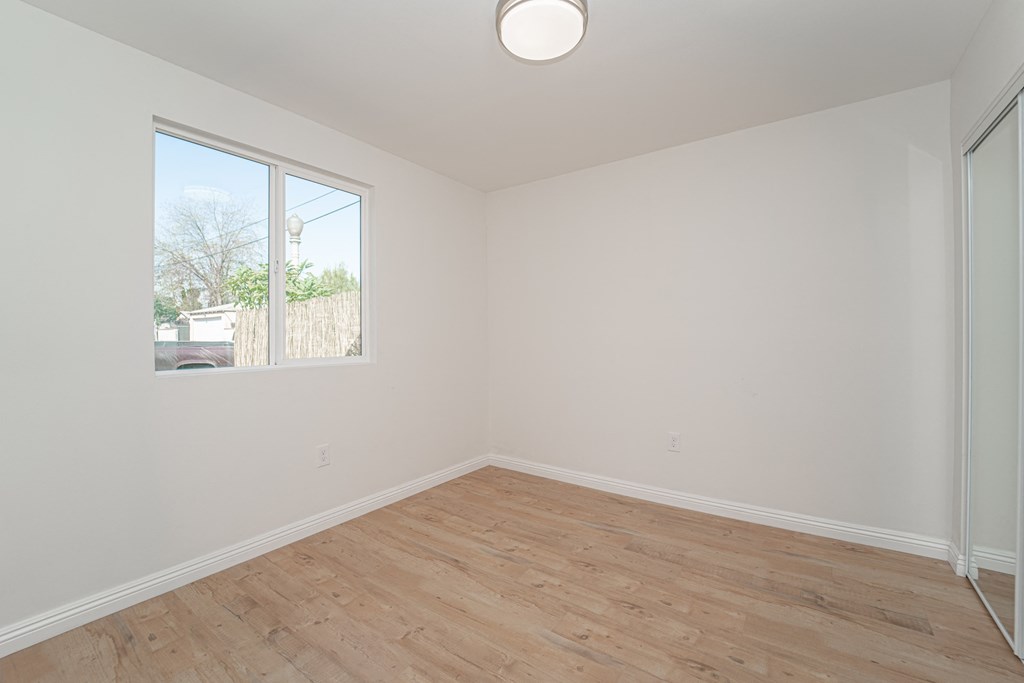 an empty room with wood floors and a window