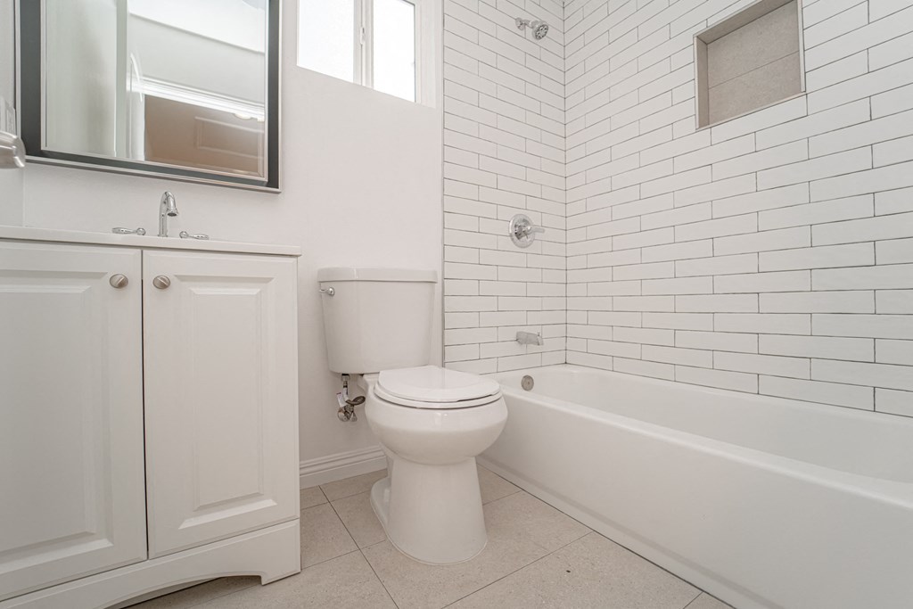 a white bathroom with a toilet and a bath tub