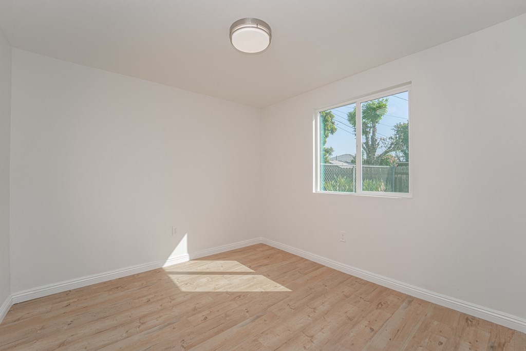 an empty room with wood floors and a window