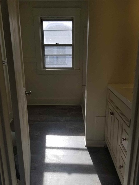 A white door is open to a hallway with a window.
