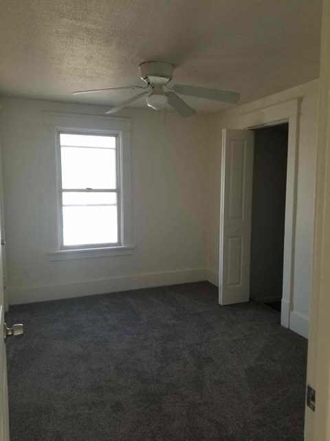 A room with a ceiling fan and a window.