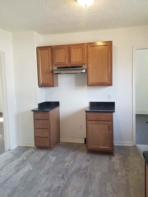 A kitchen with wooden cabinets and black countertops.
