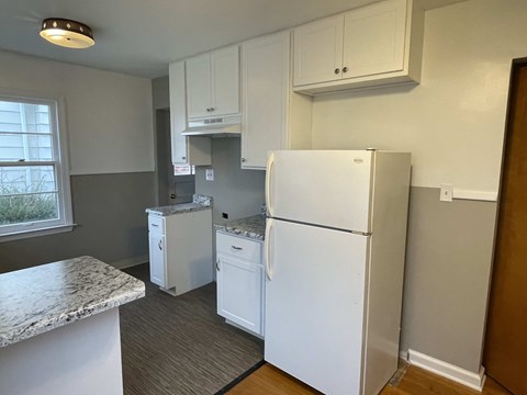 A kitchen with a white fridge, dishwasher and microwave.