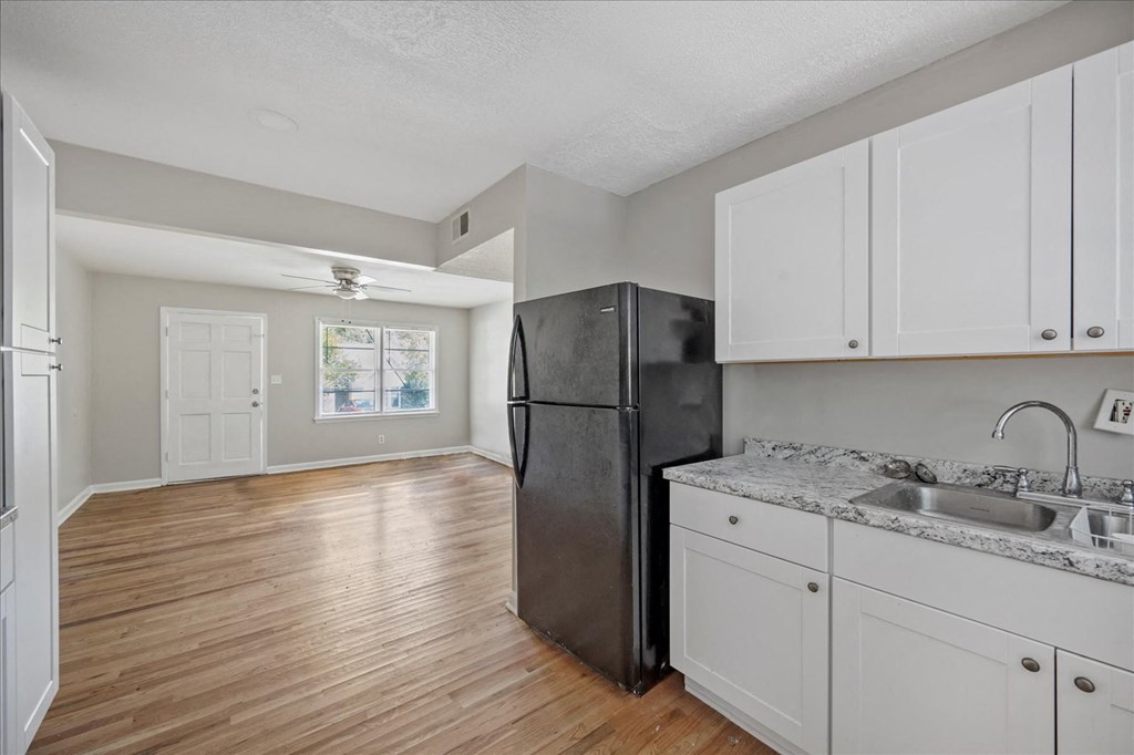 A kitchen with a black refrigerator and white cabinets.