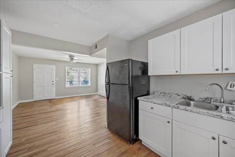 A kitchen with a black refrigerator and white cabinets.