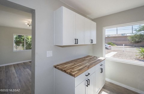 a kitchen with white cabinets and a wooden counter top