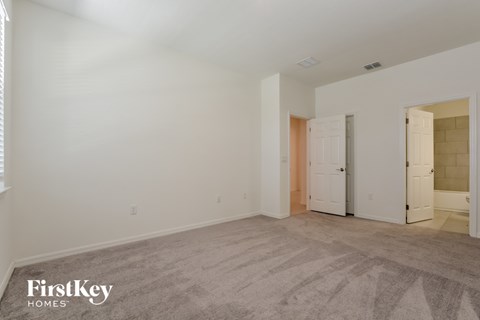 a bedroom with white walls and carpet and a door to a closet