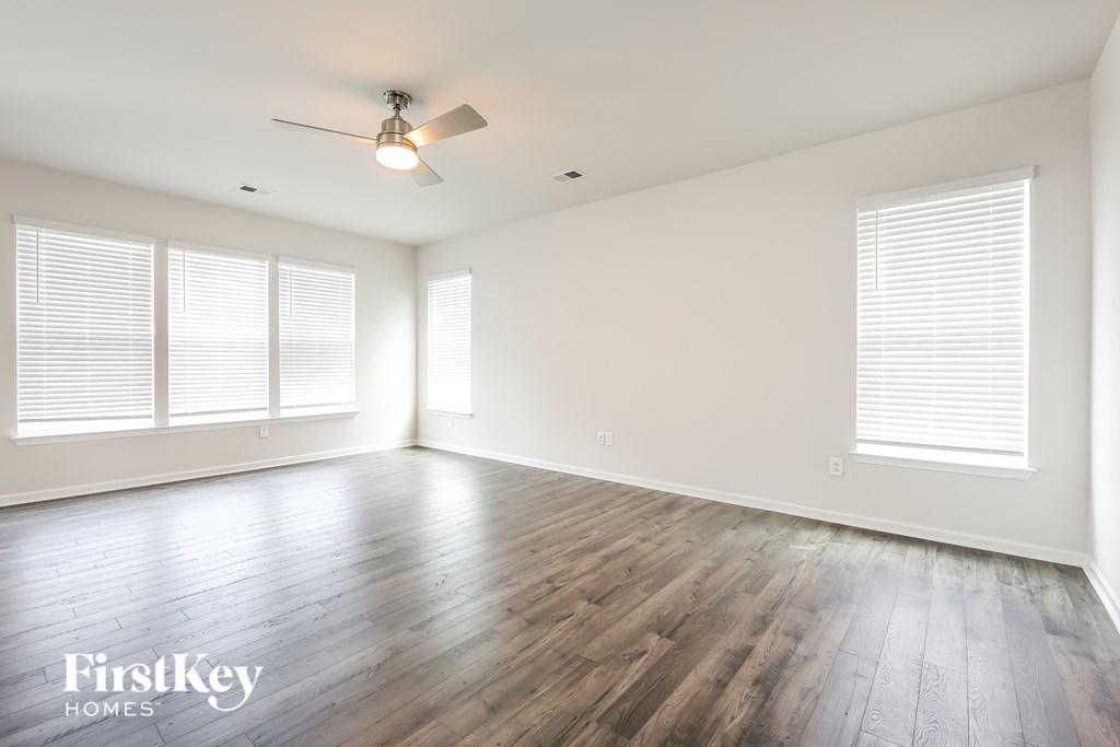 A spacious room with wooden flooring and a ceiling fan.