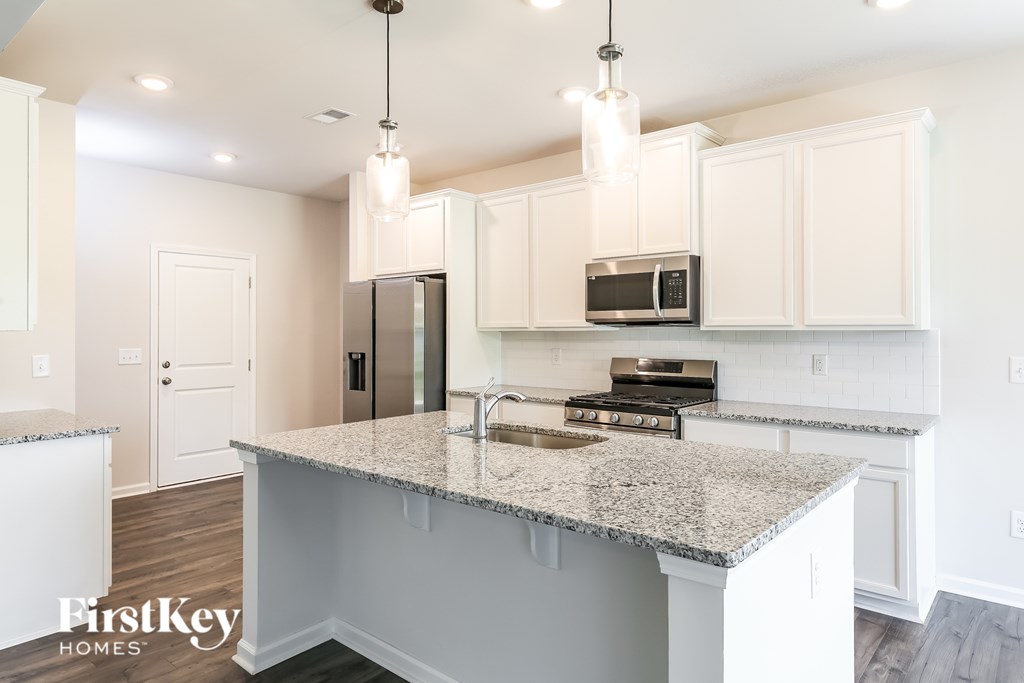 A kitchen with granite countertops and white cabinets.