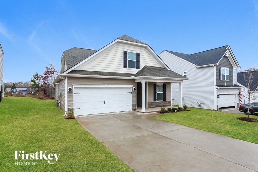 the front of a white house with a driveway in front of it