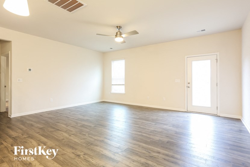 the spacious living room with wood floors and a ceiling fan