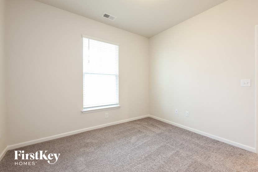 a carpeted room with a window and white walls