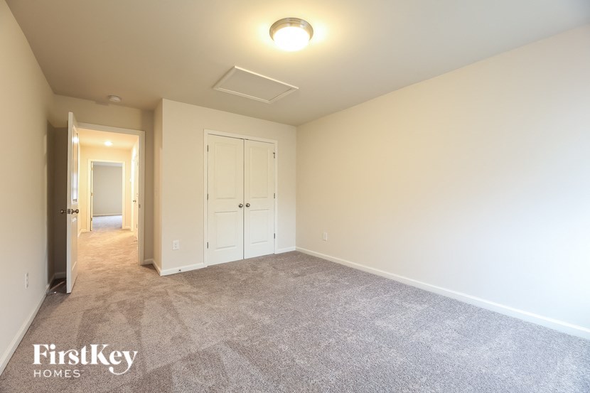 a master bedroom with carpeted flooring and a door to a closet