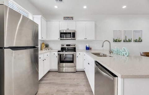 a white kitchen with stainless steel appliances and white cabinets