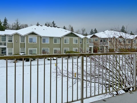 a row of houses covered in snow behind a fence