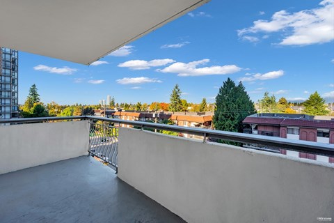 A balcony with a metal railing overlooks a cityscape.