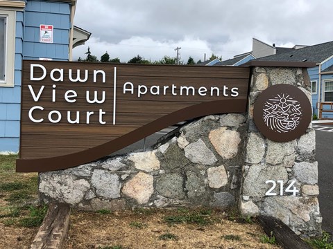 A sign for Dawn View Court apartments is displayed in front of a building.