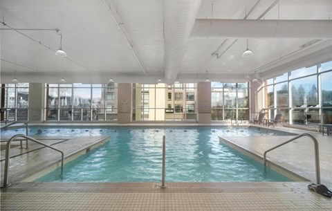 A large indoor swimming pool with a tiled floor and a glass wall.