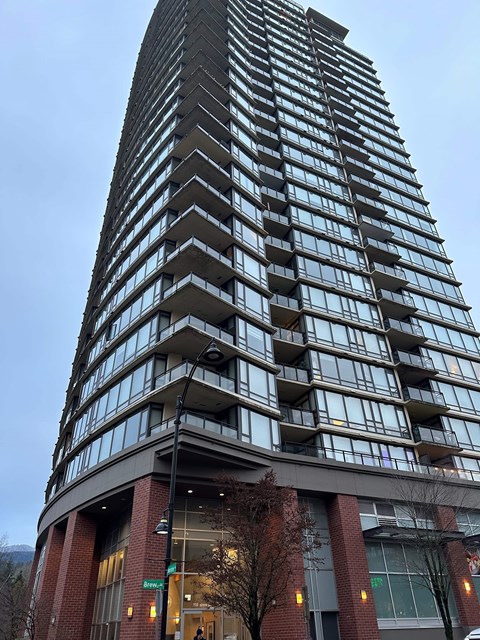 A tall building with a curved base and balconies on each floor.