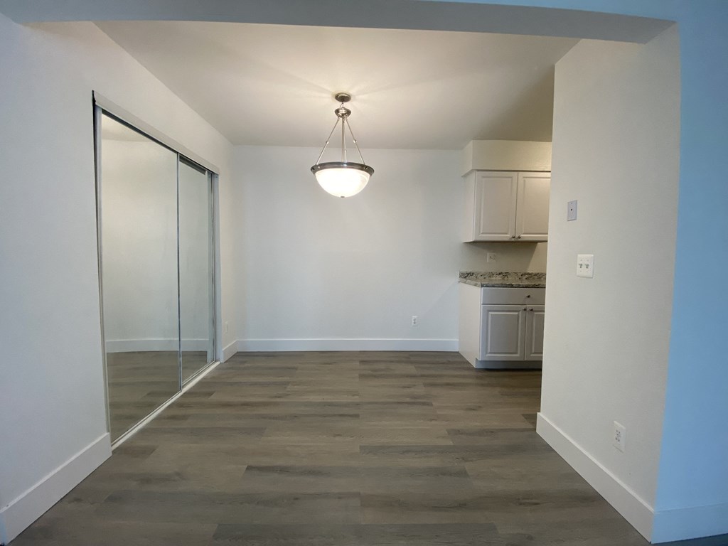 a empty living room with a sliding glass door into a kitchen
