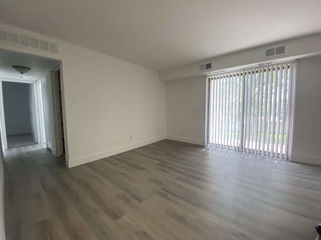 an empty living room with wood flooring and a large window