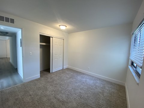 an empty living room with a door to a closet and a window