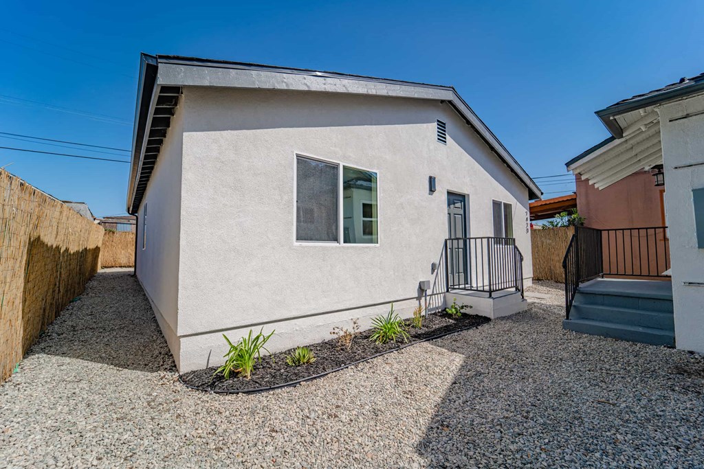 a small white house with a balcony and a staircase
