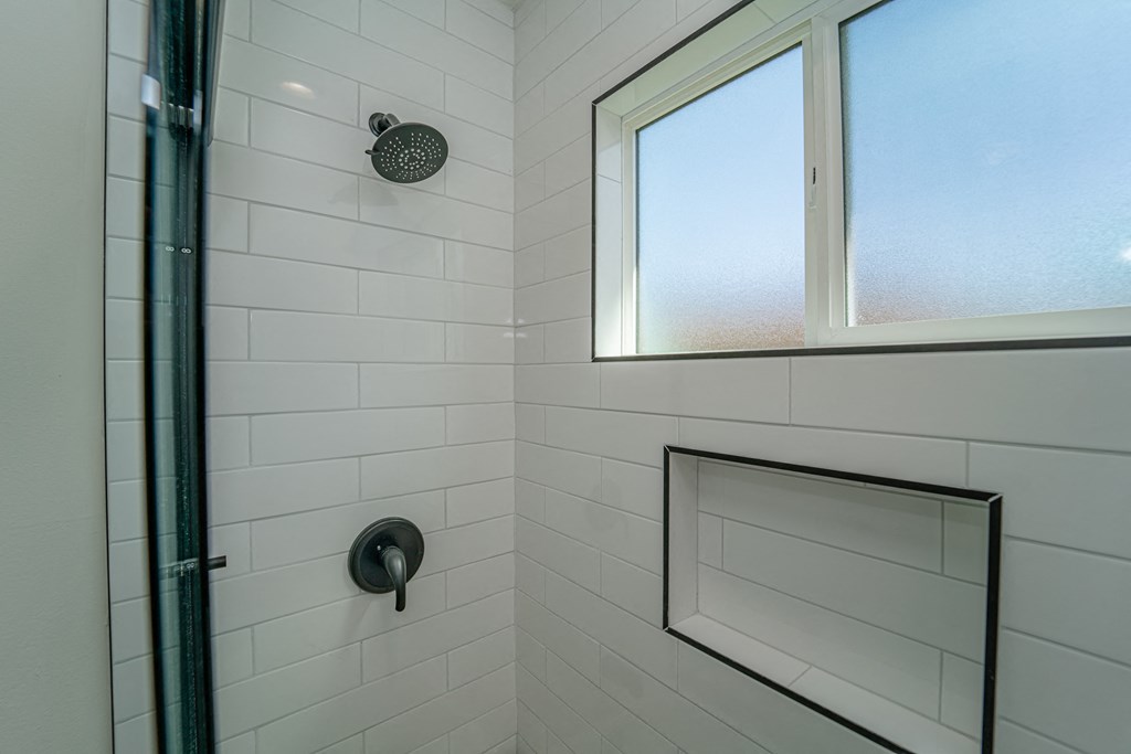 a white bathroom with a shower and a window
