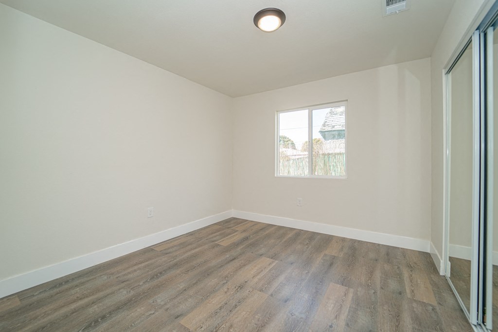 an empty living room with wood floors and a window