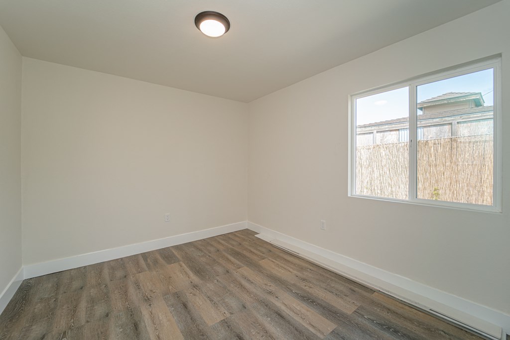 an empty room with wood floors and a window