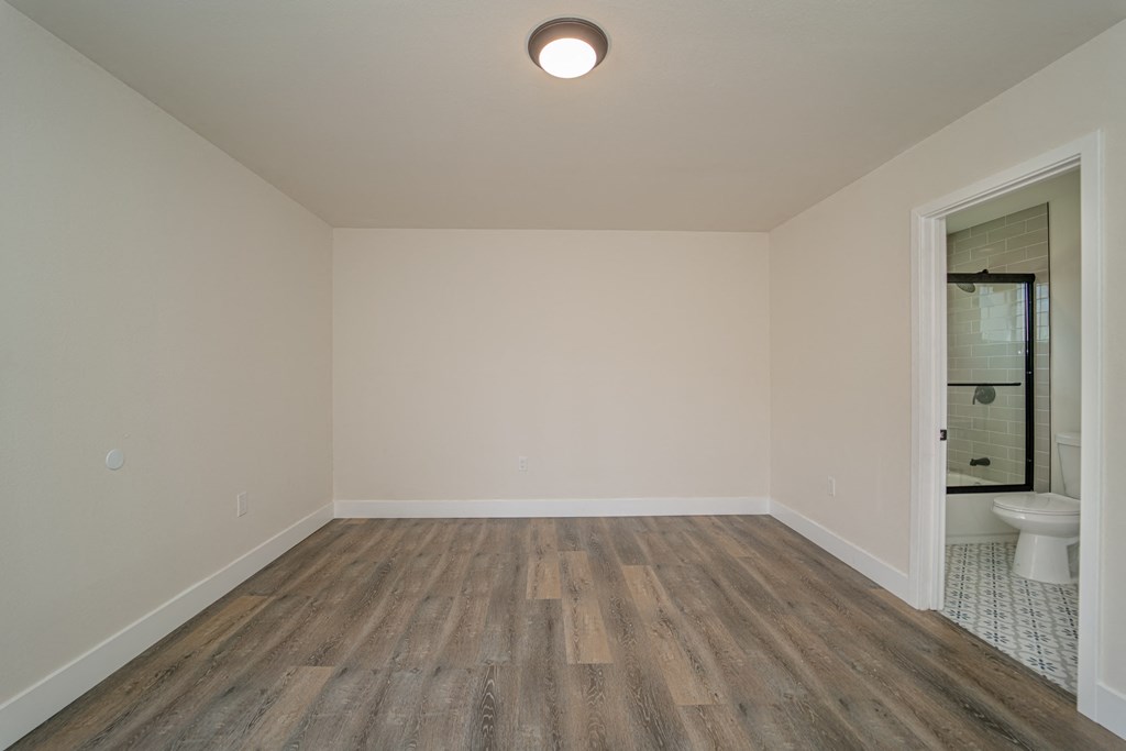 an empty living room with wood flooring and a bathroom
