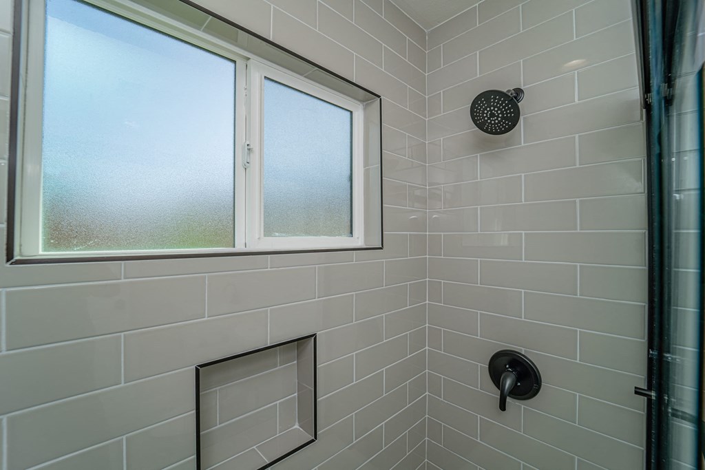 a tiled bathroom with a window and a shower